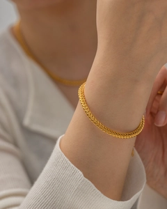 Close-up of a stylish 18K gold plated stainless steel braided bracelet on a wrist