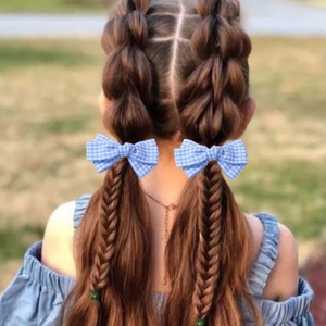 Close-up of blue checkered bow hair clips worn by a young girl with pigtails