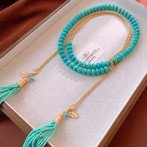 Macro shot of turquoise beads with vintage golden tassels and leaf pendants on a chain
