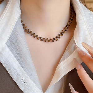Dettaglio della collana vintage con perline di occhio di tigre su modella e catena dorata
