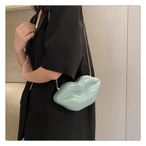 Detail of mint green lip-shaped hard shell clutch with golden chain strap and glossy finish