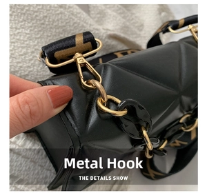 Close-up of golden metal lobster clasp and brand-patterned wide strap on black quilted bag
