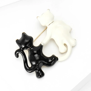 Close-up of cute black and white enamel cat brooches with polished alloy finish