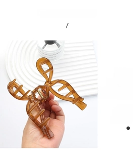Detail of amber translucent acrylic hair claw clip held by hand to show large size