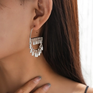Macro shot of silver semi-circle earrings with multi-row square crystal tassels on model