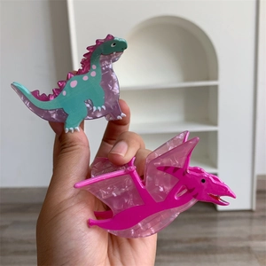 Detail of cute acrylic dinosaur hair clips in green, purple, and magenta colors