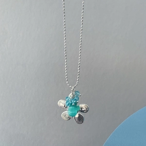 Nahaufnahme der Silberblumen-Halskette mit grünem Katzenauge und blauen Kristallen