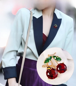 Detail of cherry brooch with red gemstones, green enamel leaves, and a gold bee pearl