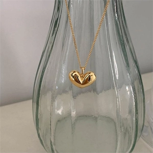 Macro view of 3D gold heart pendant with mirror-polished finish and delicate chain
