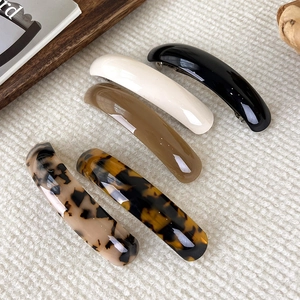 Lot de 5 barrettes à ressort en acétate poli aux couleurs tortue et unies sur tapis tricoté