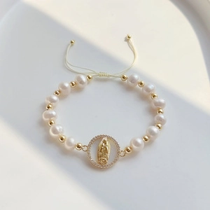 Close-up of handmade pearl bracelet with a gold Virgin Mary charm and crystal inlay