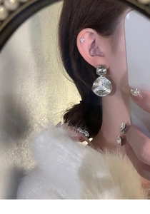 Reflet miroir montrant le mannequin portant des boucles d'oreilles rondes argentées