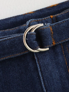 Détail du denim bleu avec coutures contrastées et boucles de ceinture en métal argenté