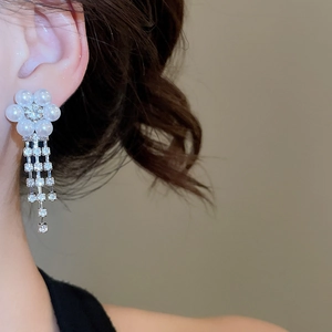 Close-up of floral pearl stud earrings with sparkling rhinestone tassels on model