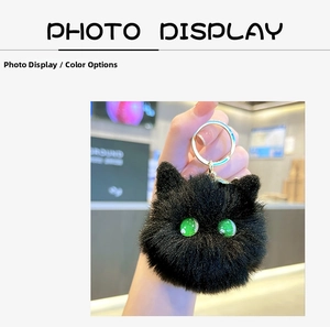 Detail of a fluffy black plush cat keychain with green eyes and a gold lobster clasp