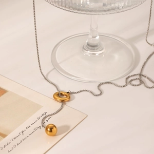 Macro view of two-tone gold and silver ball pendant necklace on elegant display