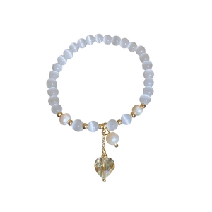 Bracelet en perles œil de chat et perles avec pendentif cœur sur fond blanc épuré