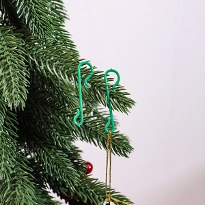 Close-up of green plastic S-shaped hooks for Christmas ornaments on tree branches