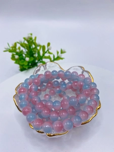 Detailed macro view of 8mm pink and blue gradient glass beads in a gold-rimmed bowl