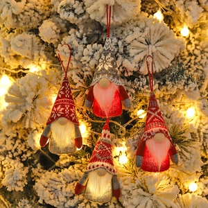 Set of 4 glowing LED Christmas gnomes hanging on a snowy tree branch with warm lights