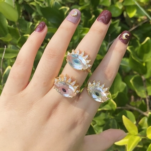 Detailed view of three gold evil eye rings with sparkling crystals on a hand
