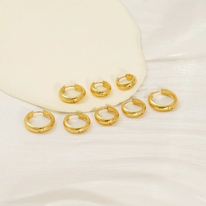 Detailed view of assorted polished gold U-shaped hoop earrings on a marble display tray