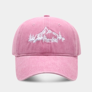 Close-up of pink washed cotton baseball cap featuring white mountain and forest embroidery