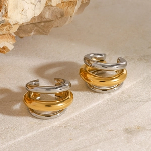 Détail macro de boucles d'oreilles étagées en acier inoxydable doré et argenté sur pierre