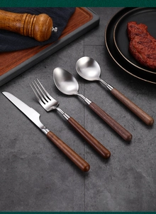 Detail view of 304 stainless steel cutlery set with walnut wood handles on dark stone