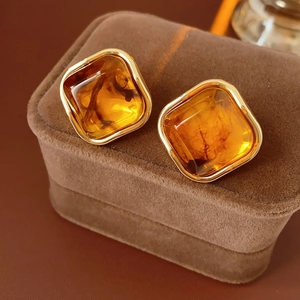 Detailed macro view of vintage gold-framed square earrings with amber gemstones