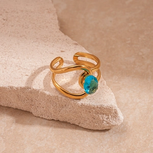 Détail d'une bague dorée double couche avec zircon bleu ovale sur pierre naturelle