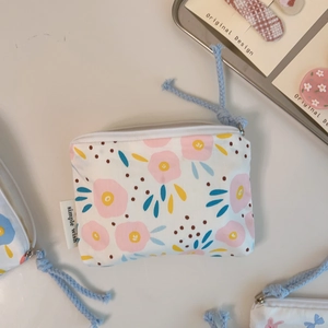 Detailed view of mini cotton pouch with floral print, zipper closure and simple wish label