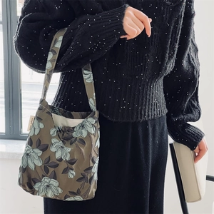 Dettaglio del tessuto jacquard floreale della borsa a spalla verde con etichetta