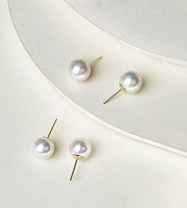 Close-up of elegant white round pearl stud earrings on minimalist curved background