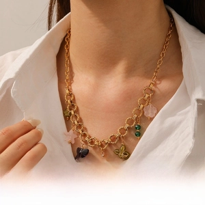Vue détaillée du collier en acier doré avec breloques papillon et coquillage en acrylique