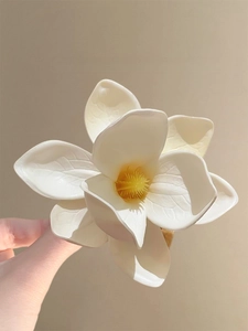 Close-up of a white frangipani flower hair clip with realistic yellow center details