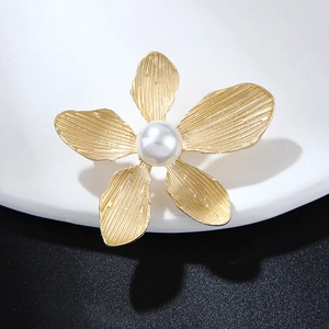 Elegant vintage gold five-petal flower brooch with a central pearl on a black background