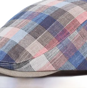 Macro shot of precise stitching and red-blue plaid texture on linen flat cap brim