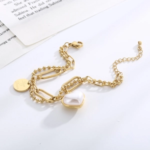 Detail of gold double-layer bracelet with heart pearl and Love Dream engraved pendant