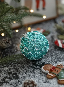 Close-up of 8cm turquoise Christmas ball with sequins and faux pearls on snowy pine branch