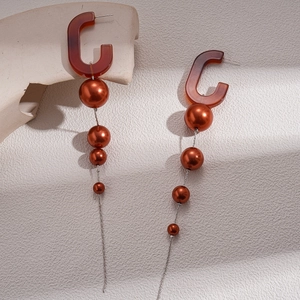 Detail of vintage long fringe earrings with C-shaped brown resin and gradient faux pearls