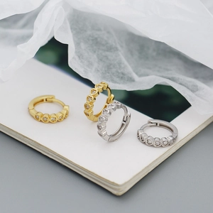 Close-up of gold and silver heart-shaped hoop earrings with sparkling zircon accents