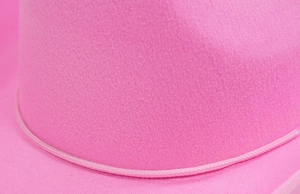 Detail eines leuchtend rosa Filzhuts mit einem dezenten geflochtenen Hutband