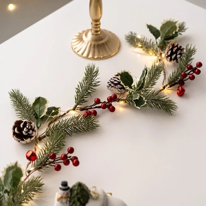 Christmas LED light string with pine cones and red berries on white festive table