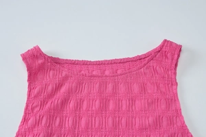 Détail du haut en tricot rose vif montrant la texture gaufrée du tissu seersucker