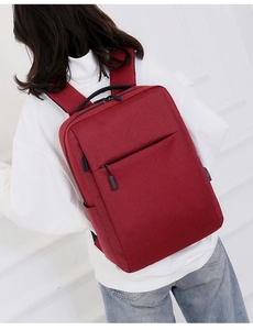 Back view of a red laptop backpack with USB charging port shown on a model