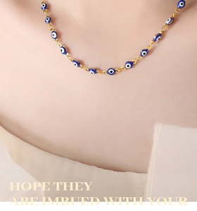Detail of evil eye pendant necklace in gold finish worn on model neck for styling