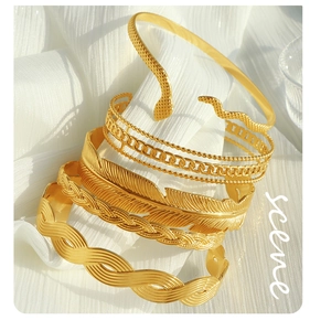 Close-up of stacked 18K gold plated bangle set with snake, feather and braided designs