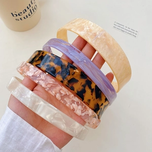 Close-up of five acetate headbands in tortoiseshell, pink marble, and solid pastel colors