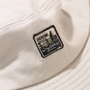 Détail d'un patch vintage et double couture sur un chapeau bob en coton beige